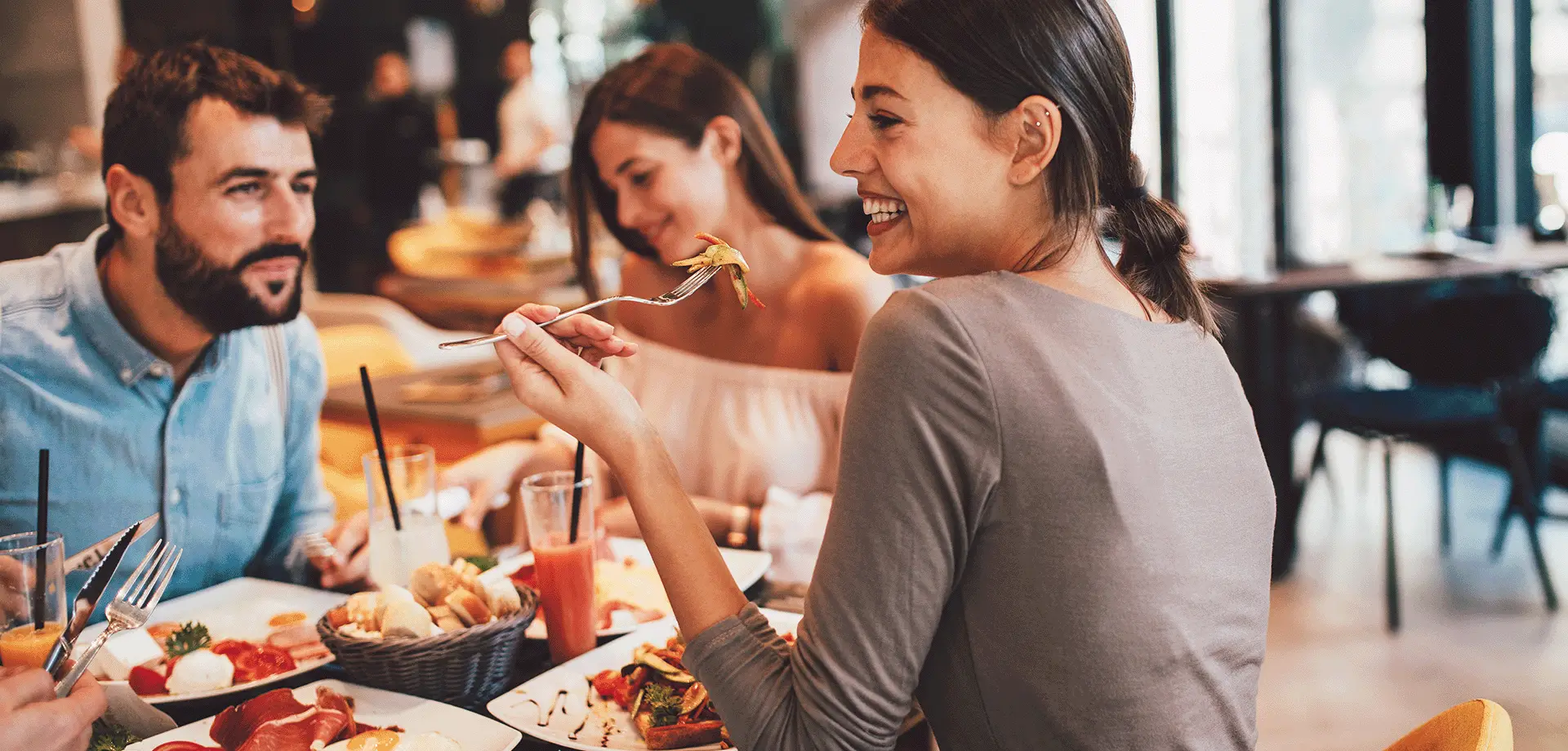A group of people laughing and enjoying a meal at a restaurant.